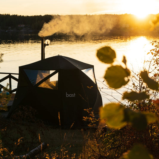 bast Saunazelt am See bei Sonnenuntergang – mobile Outdoor-Sauna mit Ofen und Blick auf das Wasser